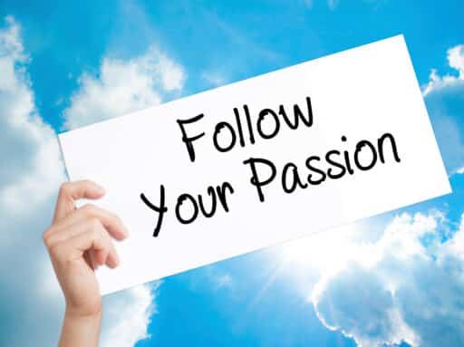 Follow Your Passion Sign on white paper. Man Hand Holding Paper with text. Isolated on sky background. Business concept. Stock Photo